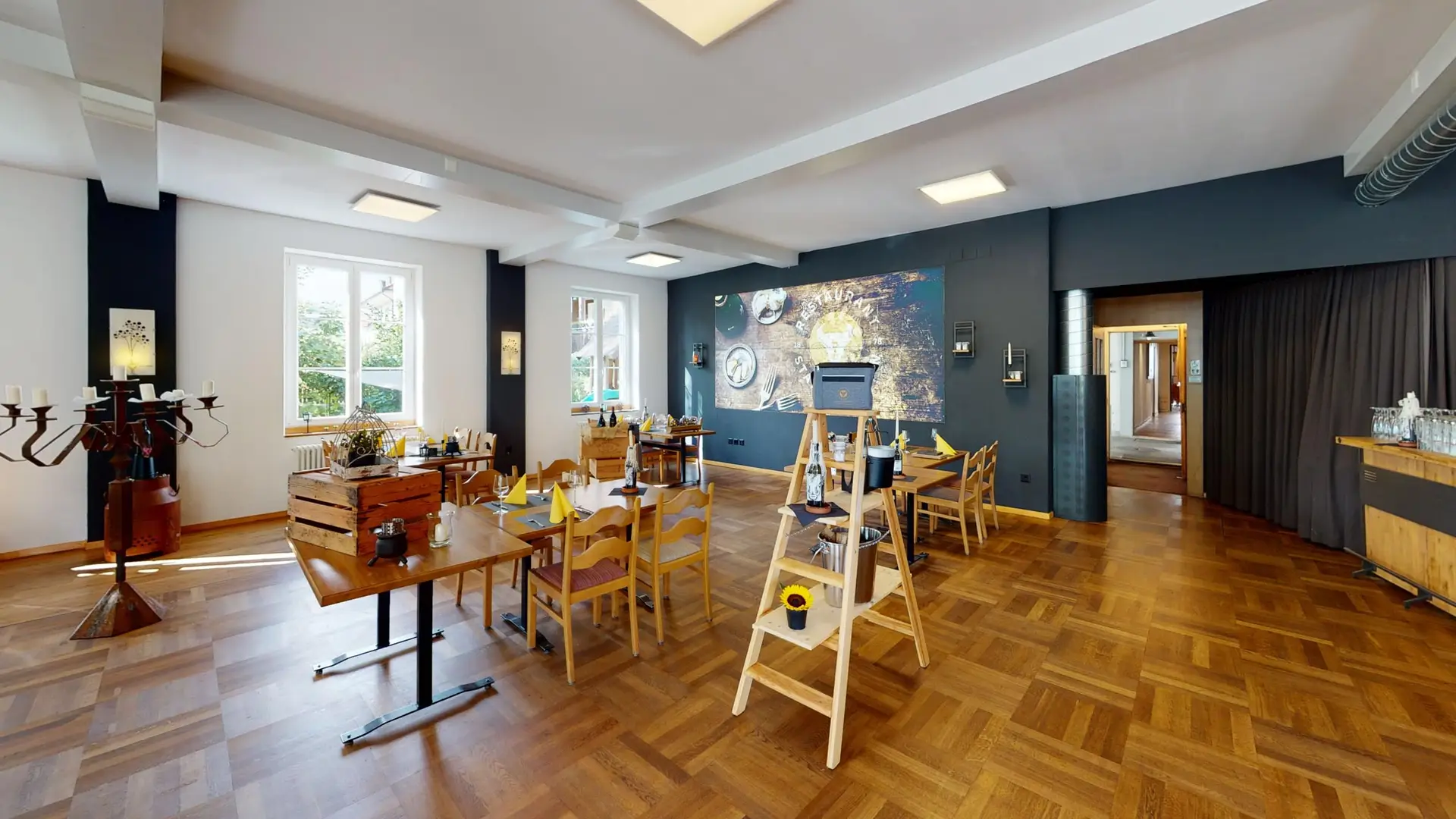 Hauptsaal des Restaurant Stadtgarten Wangen an der Aare mit Parkett, dunkler Akzentwand und gedeckten Tischen
