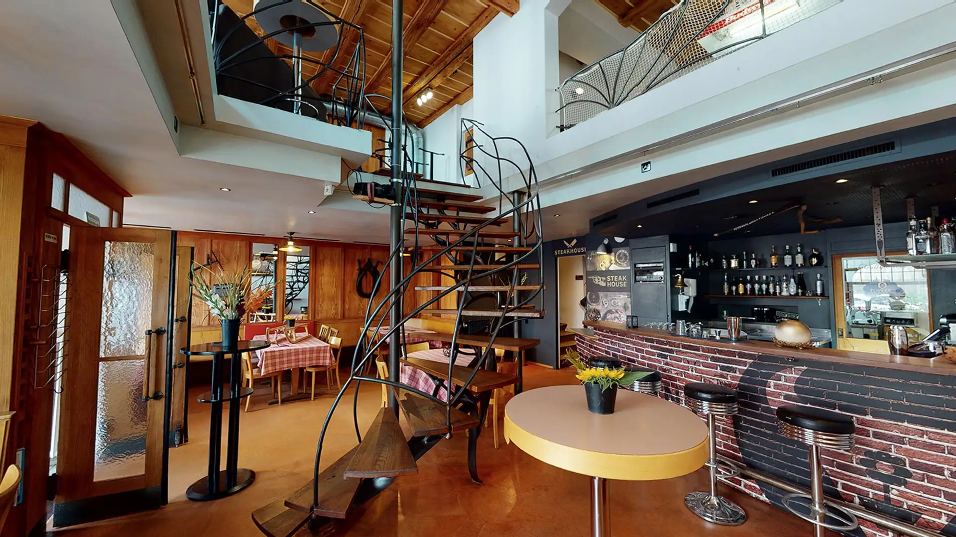 Panorama des Stübli mit Backsteinbar, Wendeltreppe und Steakhouse-Schild im Restaurant Stadtgarten Wangen