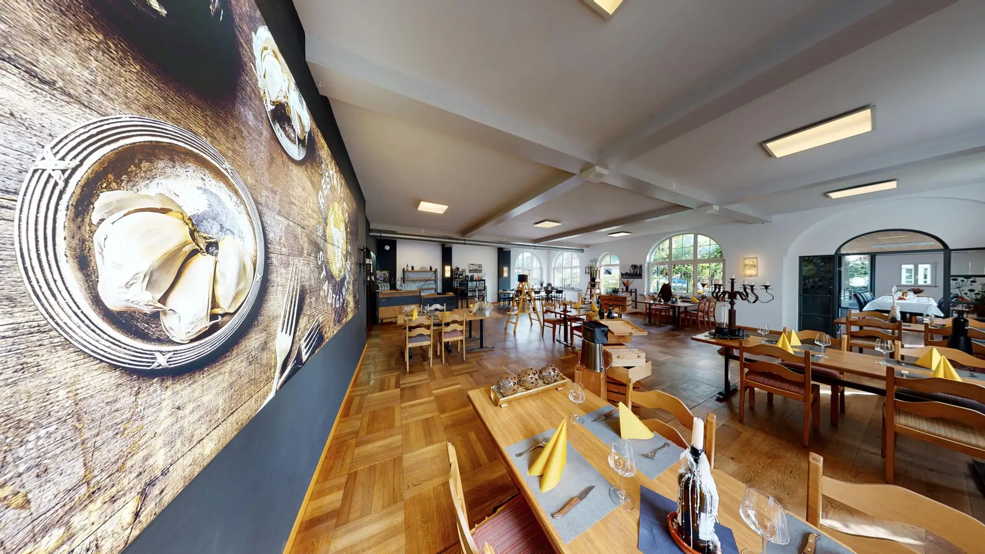 Panoramasaal mit Kunstwand und gedeckten Tischen im Restaurant Stadtgarten Wangen an der Aare