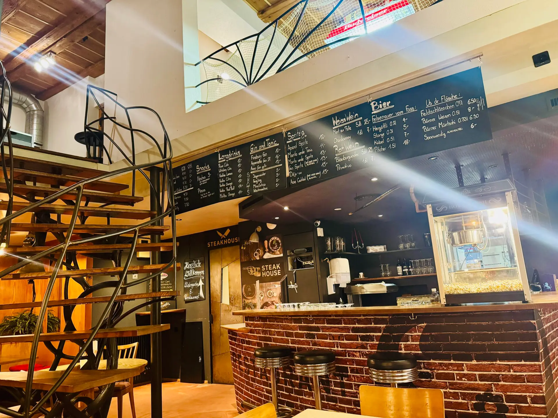 Stübli Bar im Restaurant Stadtgarten Wangen mit Backsteinbar, schwarzer Wendeltreppe und Kreide-Getränkekarte