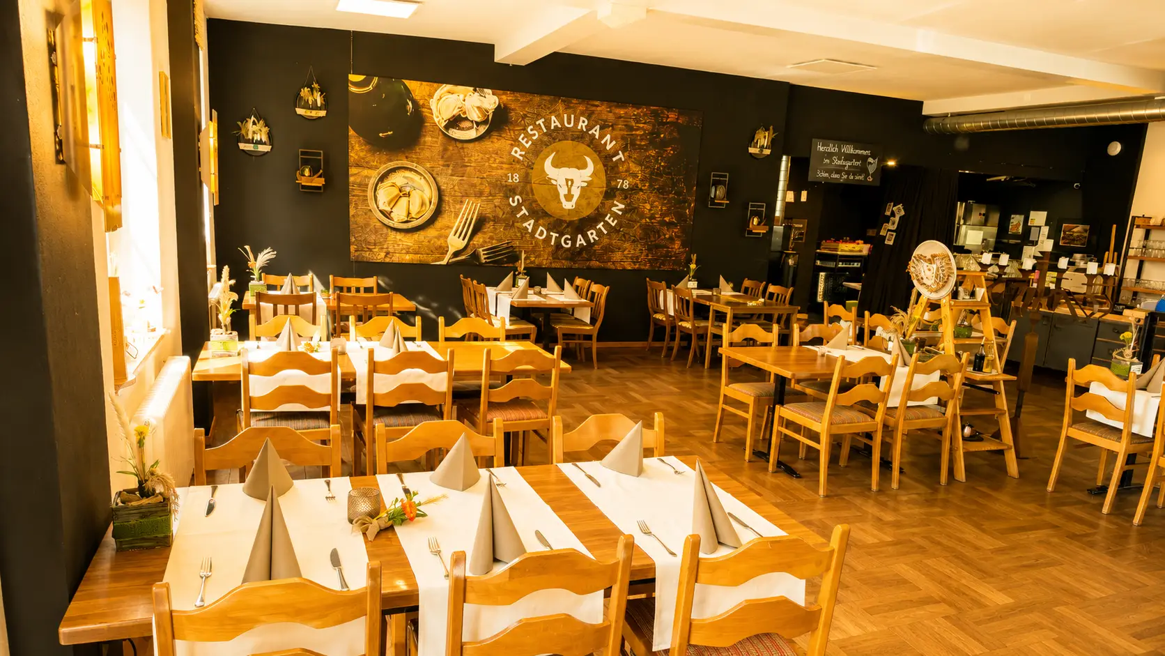 Innenansicht des Speisesaals mit Wanddekoration und gedeckten Tischen im Restaurant Stadtgarten Wangen