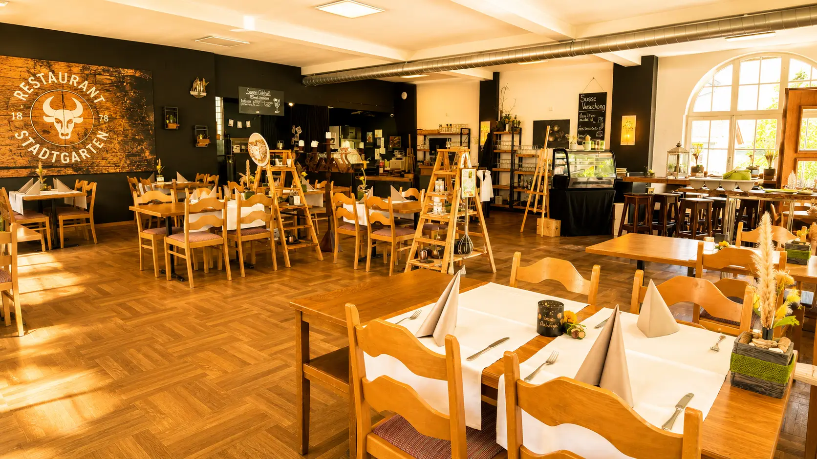 Hauptspeisesaal mit Stierkopf-Logo und eingedeckten Tischen im Restaurant Stadtgarten Wangen an der Aare