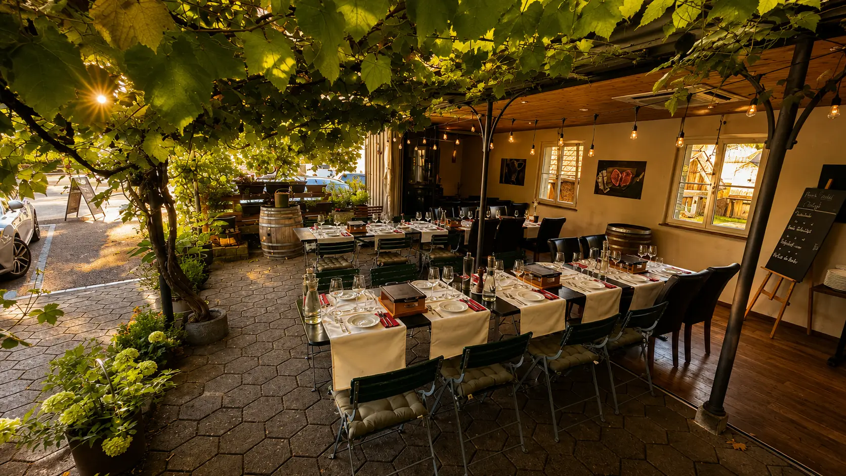 Gedeckte Tafeln mit TischGrill-Ger&auml;ten unter der Rebenpergola im Gastgarten des Restaurant Stadtgarten Wangen an der Aare