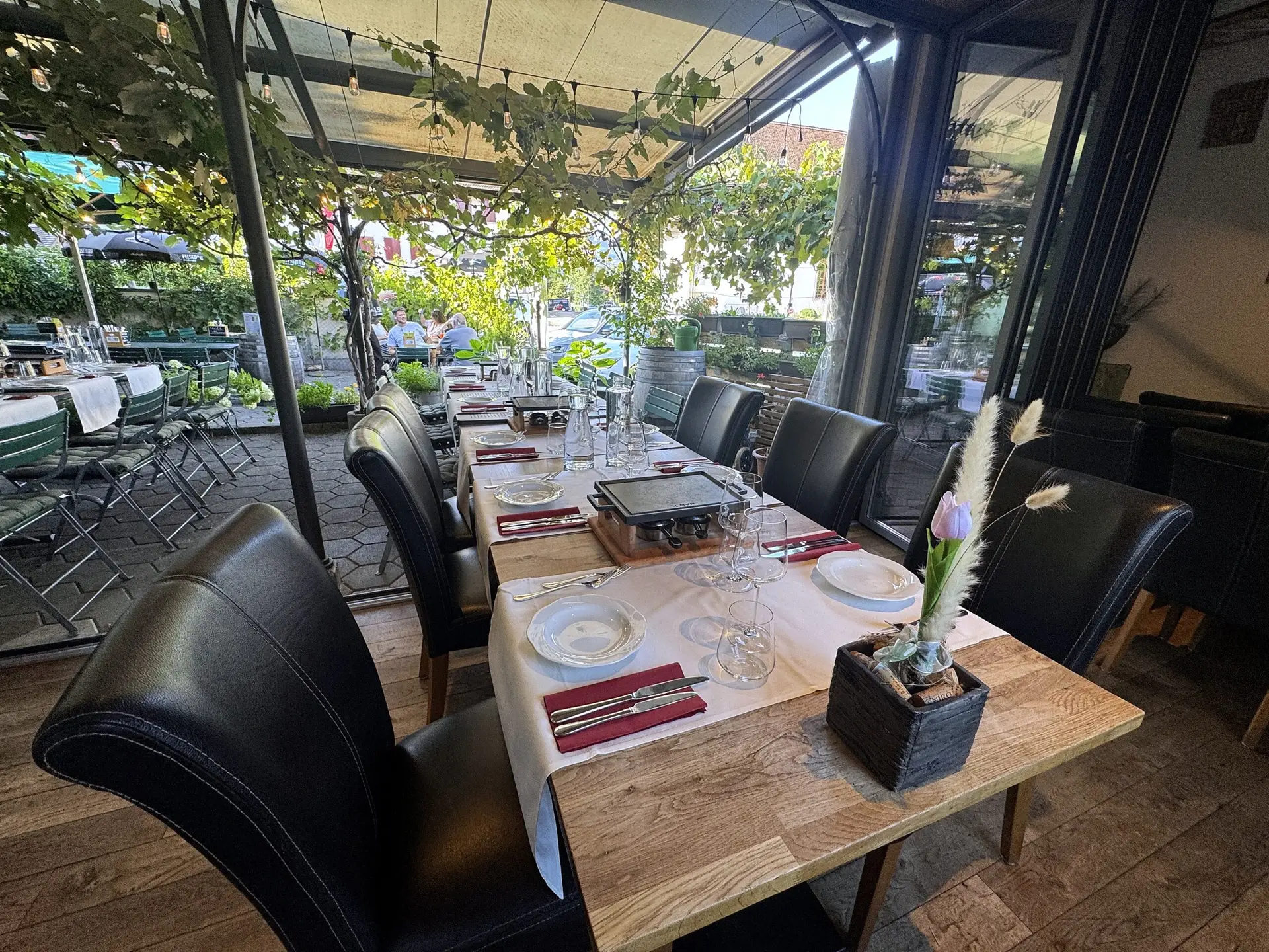 Lange gedeckte Tafel mit TischGrill-Gerät im Wintergarten des Restaurant Stadtgarten Wangen an der Aare